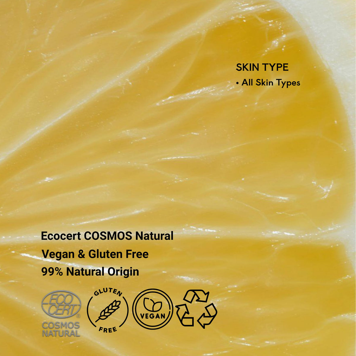 A close-up of a yellow-orange cosmetic texture or balm surface for My Spell Vitamin C serum, with overlaid text reading 'SKIN TYPE - All Skin Types' and 'Ecocert COSMOS Natural Vegan & Gluten Free 99% Natural Origin,' plus certification logos and recycling symbols.